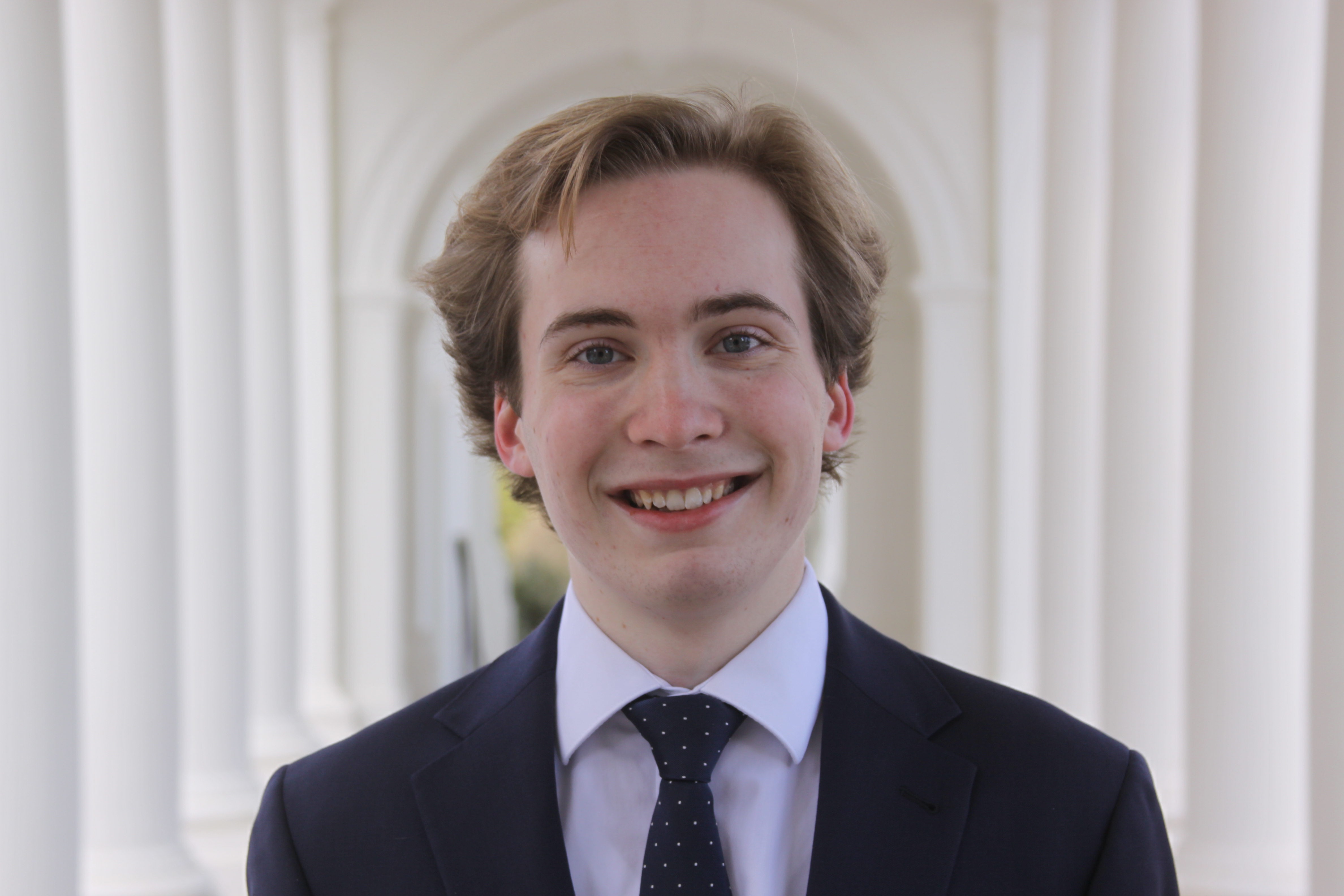 Emmett smiling in a suit in front of a white backdrop.